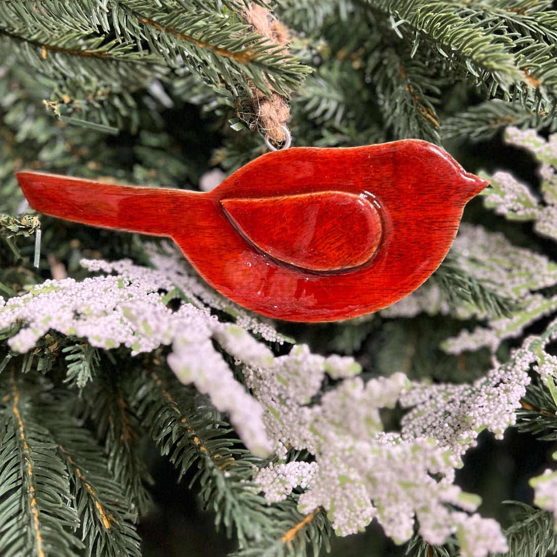 Red cardinal bird ornament on a Christmas tree with snow.