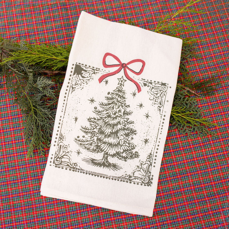 White towel with Christmas tree and bow design on a red plaid fabric background