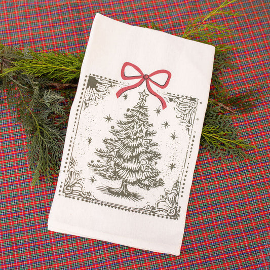 White towel with Christmas tree and bow design on a red plaid fabric background
