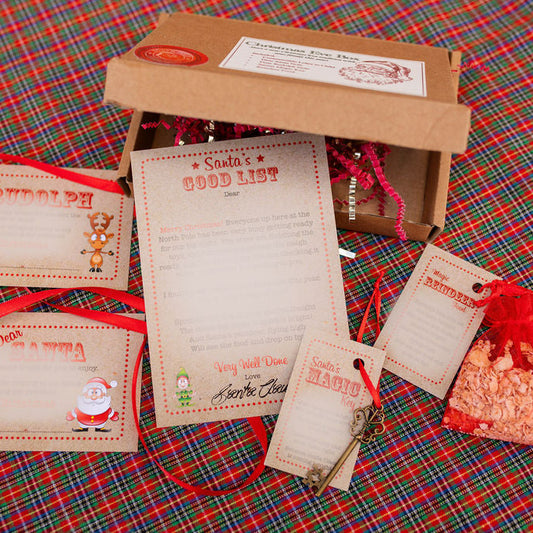 Christmas-themed gift set with letters, a box, and a small bag on a plaid fabric background.